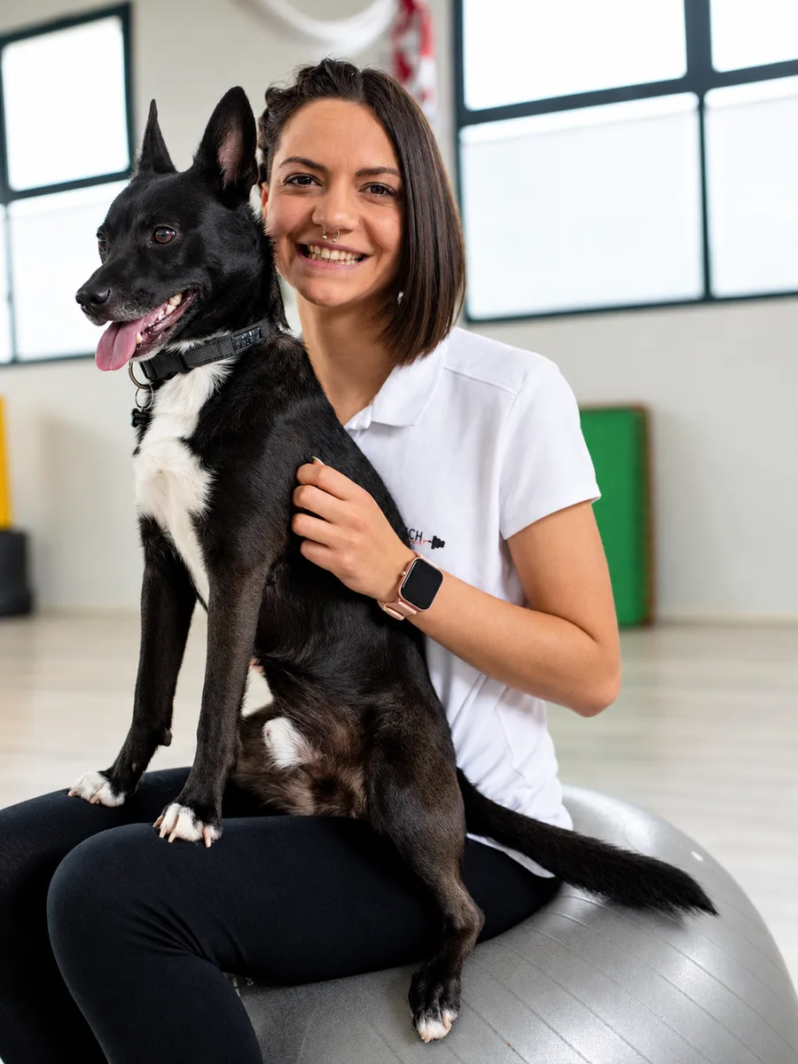 Roberta Burdese sorride in palestra con il suo cane seduta sulla palla
