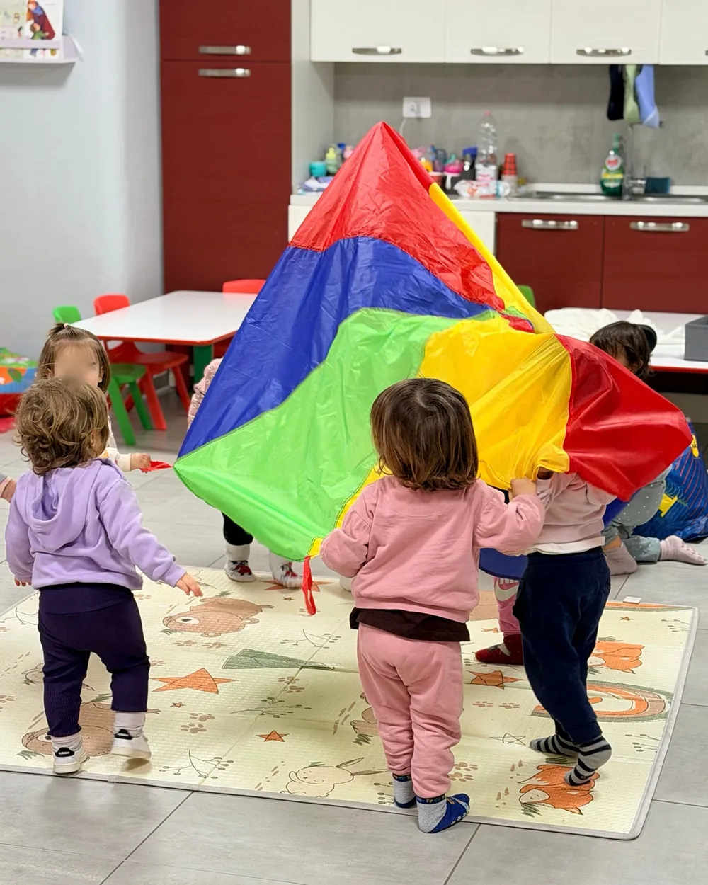 Bambini piccoli giocano con un grande telo colorato durante Crescere in Movimento